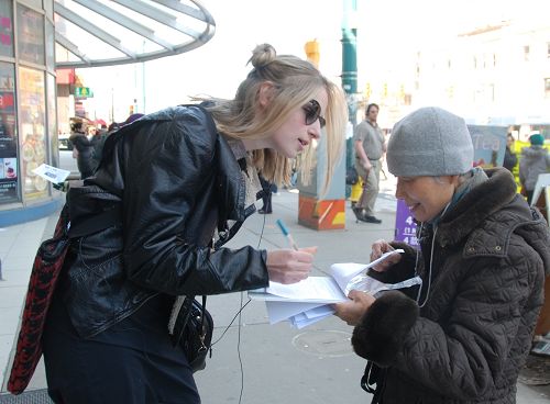 多伦多大学学生Generiere Smith（左）认真在义工递过来的征签表上签名。