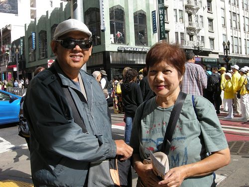 图：马来西亚华人戴先生和太太不停在给法轮功游行队伍拍照。