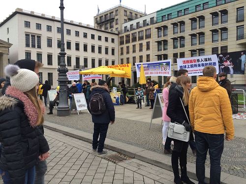 '图2：十二月十日，柏林法轮功学员在勃兰登堡门前向柏林市民和来自世界各地的游客展示法轮功功法，很多人观看。'
