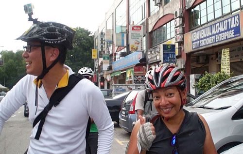'图9：一位华裔（左）与友人（右）结伴骑单车的途中，很开心遇到法轮功学员的游行，并表示非常好！'