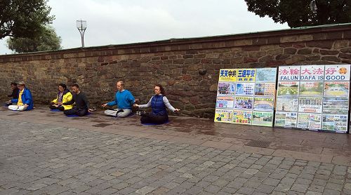 '图1：法轮功学员在斯德哥尔摩市政厅大门口前的真相点向游客演示法轮功五套功法'