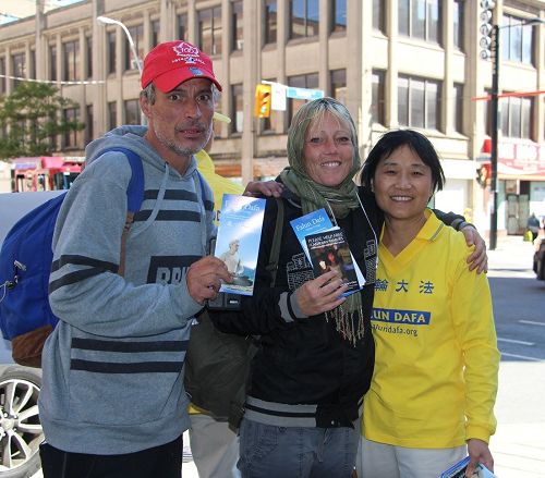 '图8：多伦多居民Patricia Dwyer（中）和她的朋友Richard Hearn与法轮功学员合影。他们拿了一叠的征签卡表示回去一定告诉更多的人签名支持。'