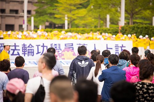 图6-7：法轮功学员在台北市政府前的市民广场举行纪念四二五活动。经过的大陆游客、市民驻足观看，并拿起手机拍照。