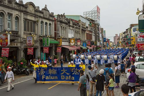 '图1：台湾法轮大法天国乐团受邀参加了台南市政府举办一年一度的“管乐艺术季”开幕大游行，有不少民众拿出手机照相留影。'