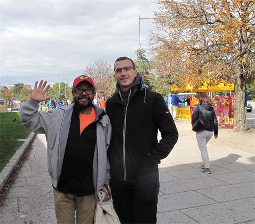 '图6：来自中美洲的卡洛斯（Calros，左）和朋友看到法轮功真相后主动向站在路边的法轮功学员表示支持'