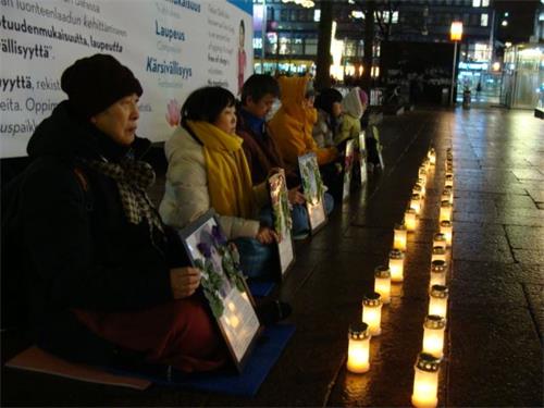 '图1-2：芬兰法轮功学员在首都赫尔辛基市中心点起烛光，悼念被中共迫害致死的中国大陆同修'