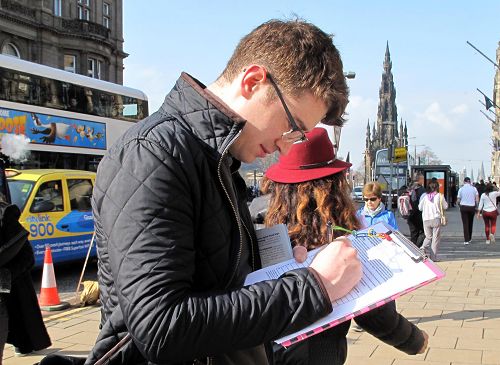 图8：苏格兰青年麦克兰•卡特（Mclain Carter）正在呼吁制止中共活摘法轮功学员器官的征签表上签名。