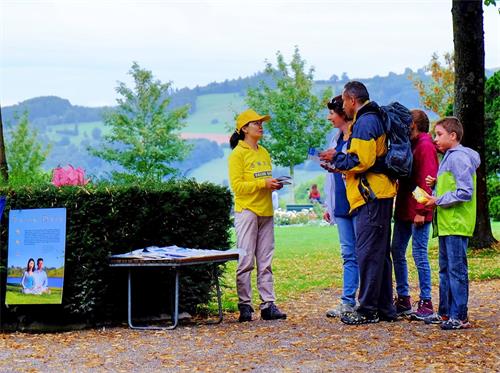 '图2：部份瑞士法轮功学员在伯尔尼景点玫瑰园（Rosengarten）炼功，向游客传播法轮功的真相，不少游客驻足了解。'