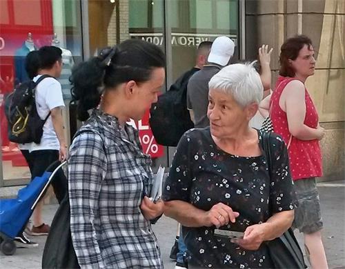 '图10：这位老年女士（右）拿着介绍法轮功和揭露中共迫害的传单，询问学员（左）有关法轮功的真相。'
