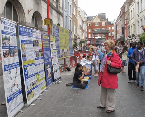 '图1～2：二零一八年八月十一日，法轮功学员在伦敦唐人街炼功、发真相传单、征签反迫害'