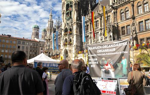 图1：二零一九年十月一日，德国法轮功学员在慕尼黑玛琳广场设立真相点，传播法轮功的真相。披露中共活体摘取法轮功学员器官的大型横幅在闹市中非常醒目。