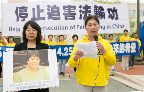 图5：于敬在集会上发言，她身旁的女士手捧法轮功学员杨晓辉的遗照。