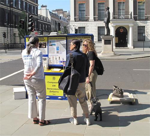 '图4：在伦敦中使馆对面，法轮功学员里拉（Lilach）在给两位路人讲真相，两人在明白真相后签名反迫害'