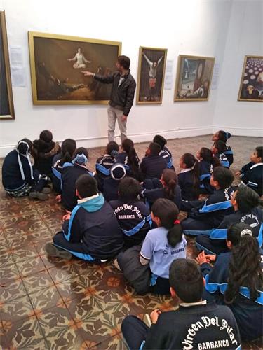 '图3：当地学校带学生集体前来观看画展，听学员解说每幅画的内涵。'