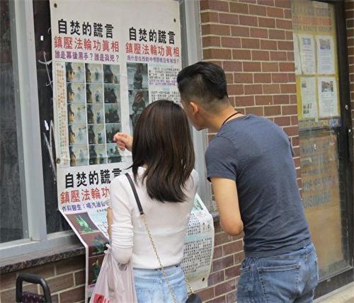 '图2：一位年轻华人在与女友观看海报时，认为中共对法轮功的迫害“没有人性”。'