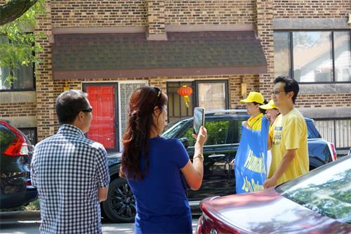 图6：路旁华裔拍摄法轮功学员的游行。
