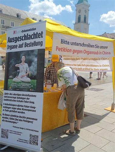 '图1～2：二零二零年七月十八日，法轮功学员在德国西南部大城市卡斯鲁尔（Karlsruhe）市中心的市场广场（Marktplatz）举办信息日活动，图为德国民众签名声援法轮功反迫害。'