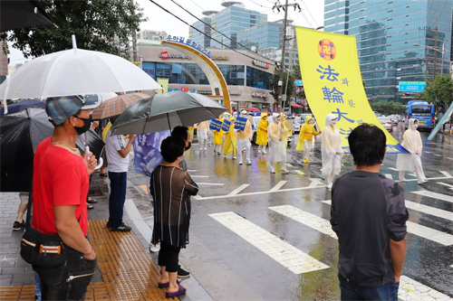 '图10～11：14：在韩国华人聚居地举行的声援3.6亿中国人三退大游行，民众在聚精会神在观看游行。'