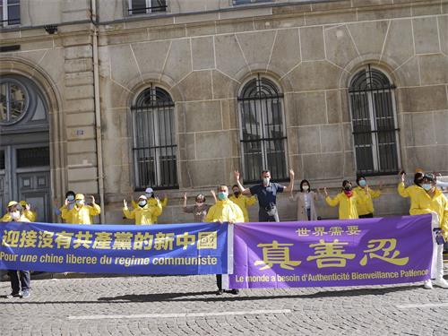 '图1～2：法轮功学员在巴黎中使馆前举行集会，告诉人们法轮功真相，揭露中共二十多年来对法轮功的残酷迫害。'