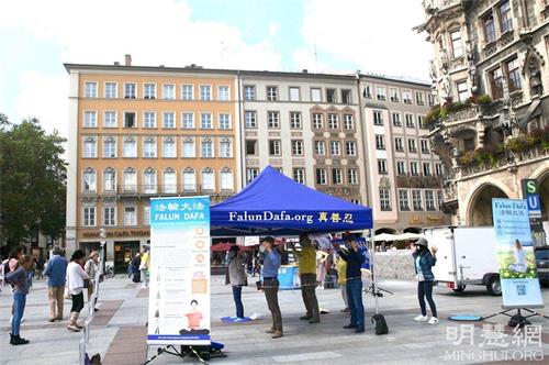 '图1：二零二一年九月一日，法轮功学员在德国慕尼黑玛琳广场（Marienplatz）举办真相日活动，图为法轮功学员展示功法。'